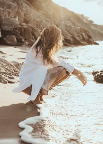 Frau hockt am Meer