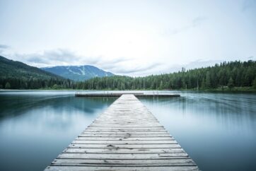 Steg im Bergsee mit Wald und Berg im Hintergrund