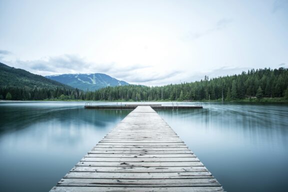 Steg im Bergsee mit Wald und Berg im Hintergrund