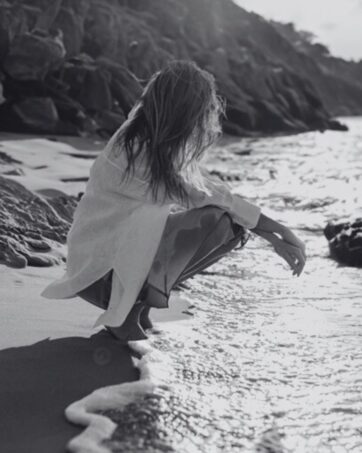 Frau hockt am Meer