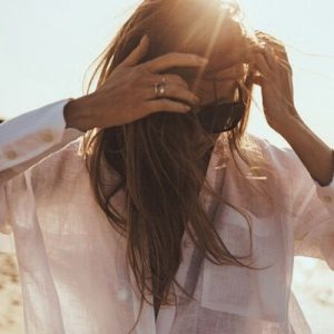 Frau im Wind mit Sonne Frau mit Sonnenbrille fährt sich durch die Haare